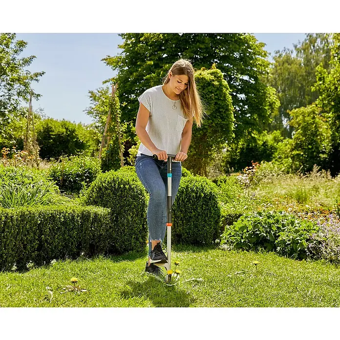 Gardena Unkrautstecher - 100 cm - Eine Frau benutzt einen Unkrautstecher, um Unkraut im Garten zu entfernen. Das Werkzeug ist ideal, um Unkraut effektiv zu beseitigen.