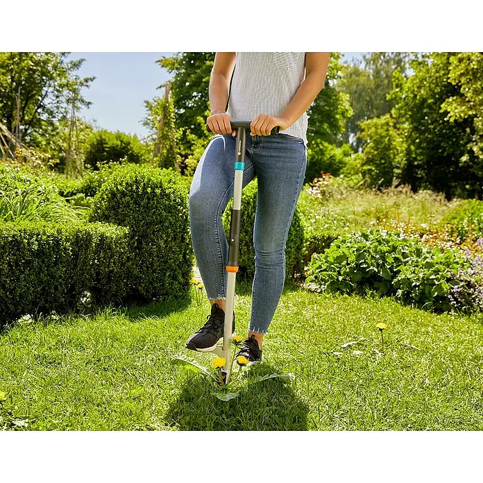 Gardena Unkrautstecher - 100 cm - Frau benutzt einen Gardena Unkrautstecher im Garten. Das Werkzeug hilft bei der einfachen Entfernung von Unkraut.
