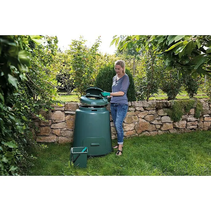 Garantia Komposter - 280 l, Ø x H: 80 x 89 cm - Eine Frau öffnet einen grünen Kompostbehälter im Garten. Der Kompostbehälter ist aus Kunststoff und hat einen Deckel, der sich öffnen lässt.