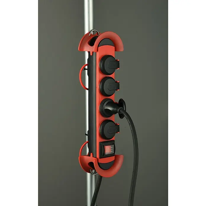 Base de enchufe múltiple - x 4, Negro/Rojo, Longitud del cable: 4 m, IP44, Con interruptor - Primer plano de una regleta roja con múltiples enchufes, sujeta a un poste, y con un cable de alimentación enchufado.