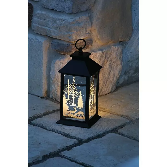 LED-Weihnachtsleuchte Laterne Vanda - Außen, Schwarz, L x B x H: 14 x 14 x 27 cm - Schwarze Laterne mit beleuchteter Winterlandschaft (Hirsche, Bäume) auf Steinplatten, neben einer Steinmauer.