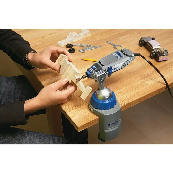 Dremel Multifunktionswerkzeug 3000-15 - 130 W - Der Dremel Multischraubstock ist auf einer Holzoberfläche befestigt und wird zum Schleifen eines kleinen Holzstücks verwendet.