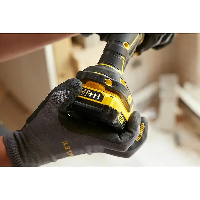 Stanley FatMax Taladro atornillador de batería SFMCD720D2K - 18 V, 2 baterías, 2 Ah, 80 Nm - Primer plano de un taladro inalámbrico amarillo Stanley V20 que sostiene una persona con guantes de trabajo grises Stanley.