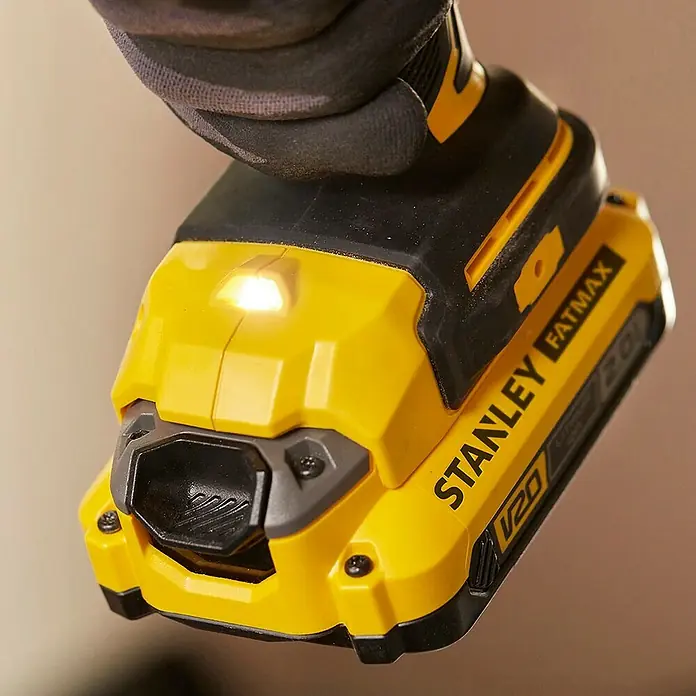 Stanley FatMax Taladro atornillador de batería SFMCD720D2K - 18 V, 2 baterías, 2 Ah, 80 Nm - Primer plano de una herramienta inalámbrica amarilla Stanley Fatmax V20 con una luz LED brillante, sostenida por una mano enguantada.