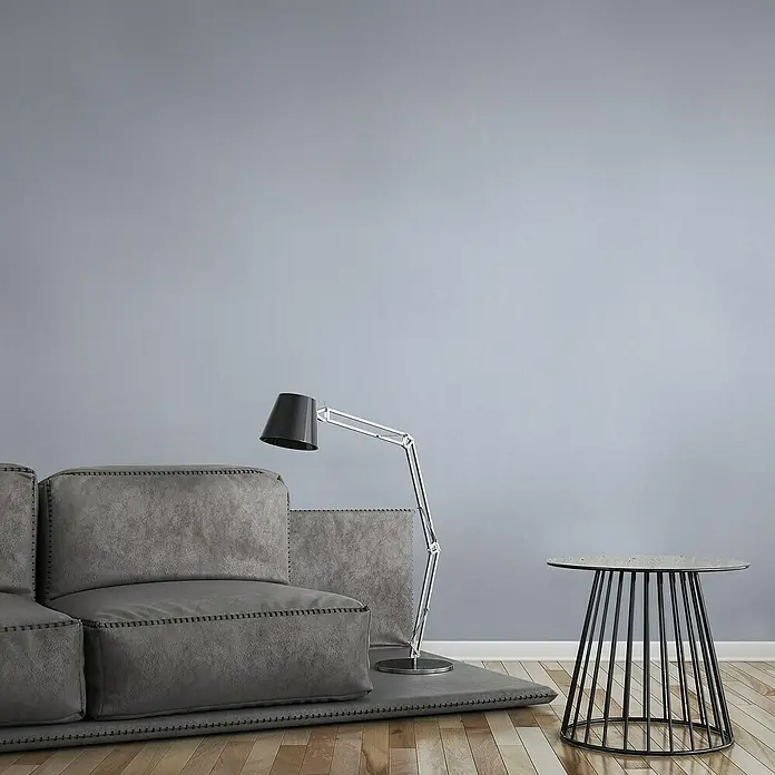 A.S. Création Vliestapete - Blau, Uni, 10,05 x 0,53 m - Graues modulares Sofa mit Stehlampe und Beistelltisch auf Holzboden vor grauer Wand. Das Sofa ist der Hingucker in diesem Bild.