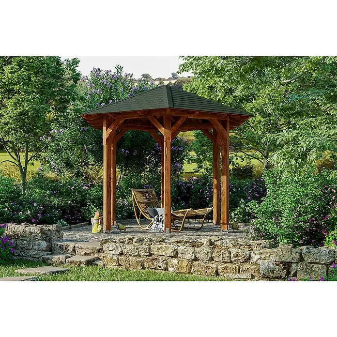 SKAN HOLZ Pavillon Colmar 1 - L x B: 312 x 360 cm, Nussbaum - Das Foto zeigt einen Holzpavillon im Garten mit Möbeln zum Entspannen, umgeben von blühenden Büschen und einer Steinmauer.