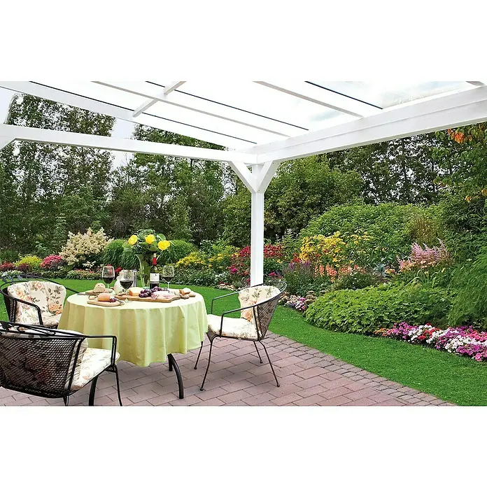 Skan Holz Terrassenüberdachung SanremoB x T: 434 x 250 cm, Weiß, Fichtenholz - Ein einladender Gartentisch unter einer Pergola, gedeckt mit Wein, Käse und Brot, umgeben von blühenden Pflanzen und Stühlen.