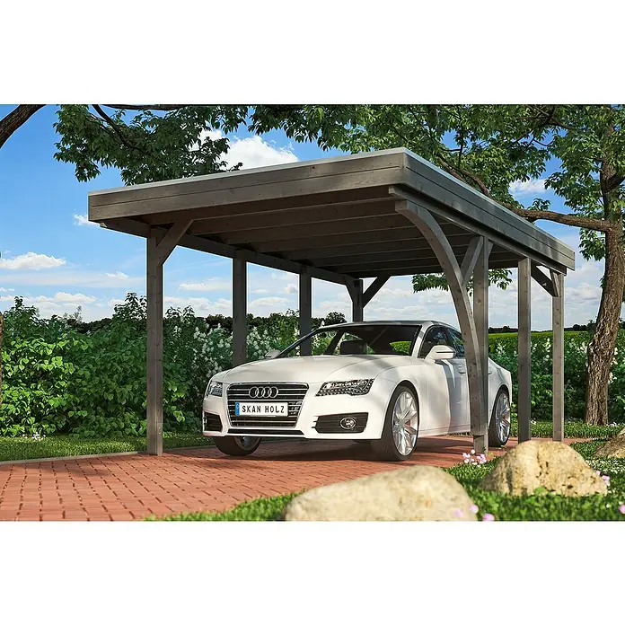 SKAN HOLZ Carport Friesland - Außenmaß inkl. Dachüberstand (B x T): 3,14 x 5,55 m, Einzelcarport, Schiefergrau, Mit 1 Einfahrtsbogen - Ein weißes Auto parkt unter einem Holzcarport mit Flachdach, umgeben von üppigem Grün und rotem Pflaster. Idealer Schutz für Ihr Fahrzeug!