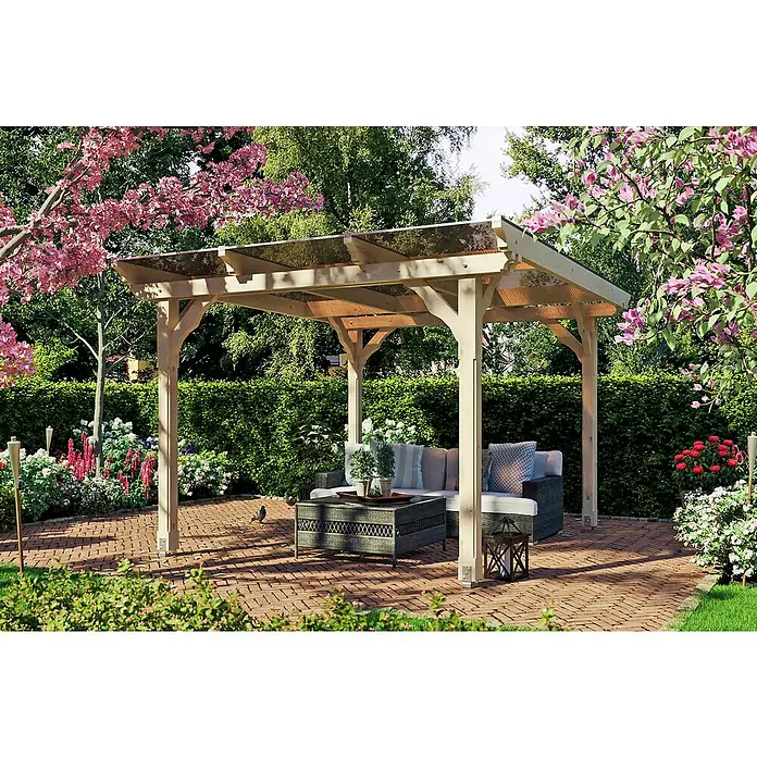 SKAN HOLZ Pavillon Marseille - L x B: 350 x 327 cm, Natur - Diese Aufnahme zeigt eine stilvolle Pergola mit Glasdach und Sitzmöbeln auf einer Terrasse, umgeben von üppiger Vegetation und Blumen.