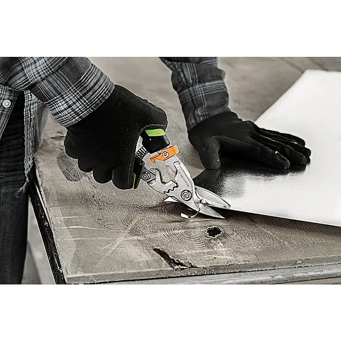 Fiskars PowerGear Tijeras para chapa - Largo: 29 cm, Longitud de corte: 38,1 mm, Acero inoxidable, Negro/Verde - Una persona cortando lámina con tijeras Fiskars, con mango verde y mecanismo de bloqueo naranja para seguridad.