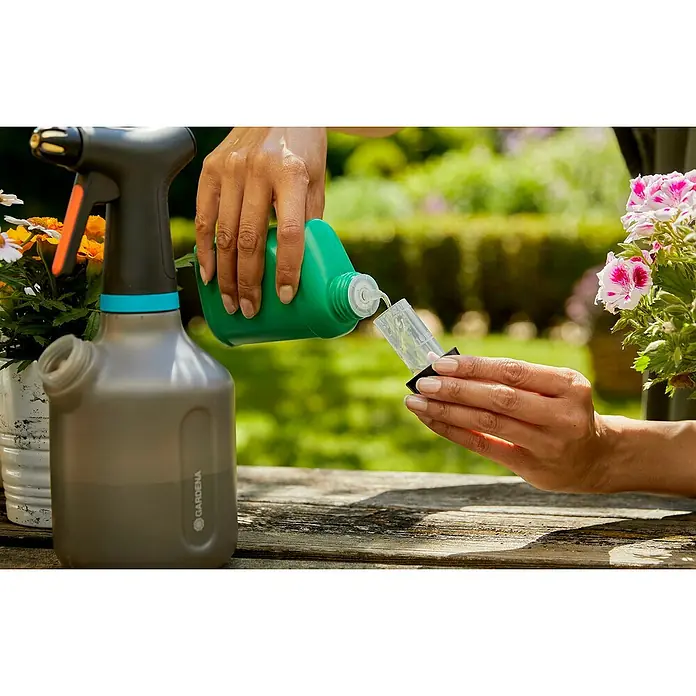 Gardena Handsprüher - 1 l - Gießkanne wird mit Flüssigkeit aus einer grünen Flasche befüllt, um Pflanzen zu bewässern.