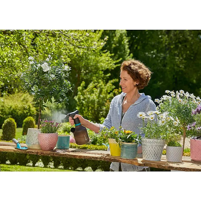 Gardena Pulverizador con bombeo - 1 l, Antracita - Una mujer riega las plantas con un pulverizador a presión GARDENA. Ideal para el cuidado de plantas en casa y jardín, fácil de usar.