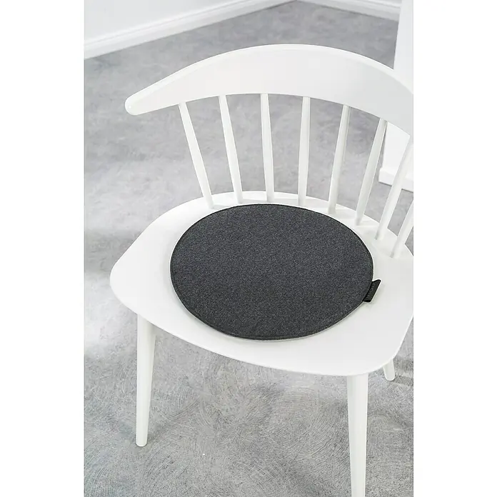Sitzkissen rund Carl - Ø x H: 35 x 2 cm, Anthrazit, 100 % Polyester - Grauer Sitzkissen auf einem weißen Stuhl. Das runde Kissen bietet Komfort und Stil, perfekt für jede Inneneinrichtung.