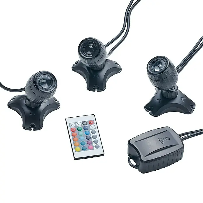 Pontec Teichbeleuchtung PondoStar LED - 3 Stk., Lichtfarbe: RGB - Nahaufnahme von drei schwarzen LED-Spotleuchten mit einer Fernbedienung und einem Netzteil auf schwarzem Hintergrund.