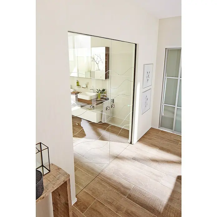 Knauf Klemmbacken Pocket Kit - Belastbarkeit pro Tür: 120 kg, Passend für: Glastürblätter mit Glasdicken 8/10/12 mm VSG/ESG - Helles Badezimmer mit einer modernen Glasschiebetür, die mit eleganten Wellenlinien verziert ist. Das Design schafft eine offene und stilvolle Atmosphäre.