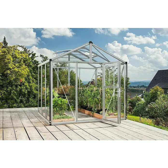 Vitavia Gewächshaus Zeus 6200 - Außenmaß inkl. Dachüberstand (B x T): 258,4 x 242 cm, 3 mm, Aluminium - Das Bild zeigt ein Gewächshaus aus Glas und Metall mit Pflanzen darin auf einer Holzterrasse im Garten unter blauem Himmel.