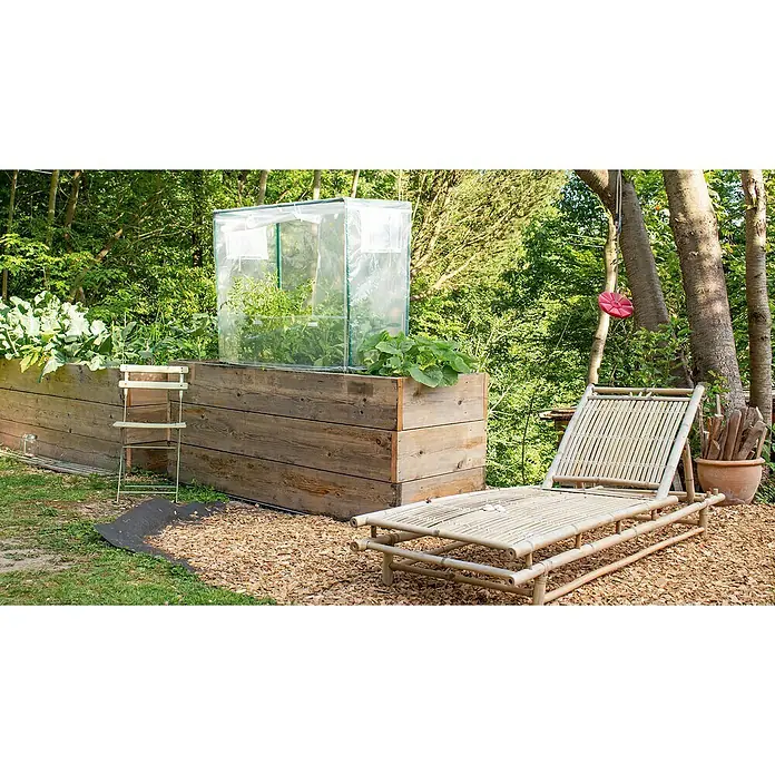 Vitavia Hochbeet-Abdeckung - L x B x H: 88 x 55 x 105 cm - Ein einstöckiges Hochbeet aus Holz mit einem Mini-Gewächshaus darauf, daneben eine Bambusliege und ein Baum mit Schaukel.