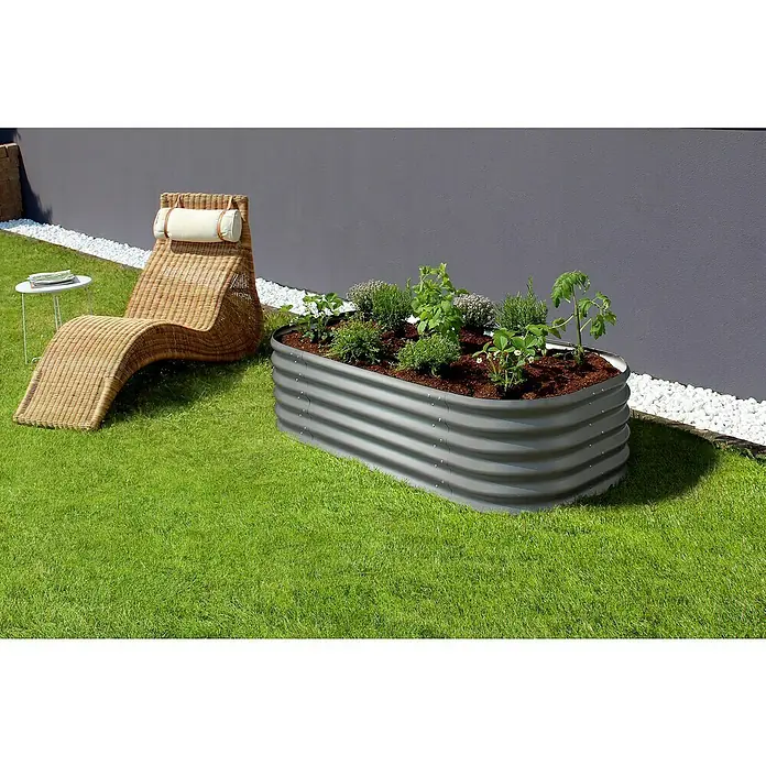 Vitavia Hochbeet Terra 401 - 162 x 82 x 40,1 cm, Zincalume®, Granit - Ein erhöhtes Gartenbeet aus grauem Metall mit Bepflanzung im Garten, neben einem Korbstuhl. Das perfekte Beet für Kräuter und Gemüse.