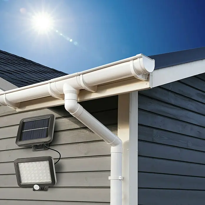 BAUHAUS Solar-Außenwandleuchte - 3 W, Schwarz, IP44, 300 lm - Bild einer Hauswand mit einer Solarleuchte und einem Bewegungssensorlicht darunter, die eine energieeffiziente Beleuchtungslösung bieten.