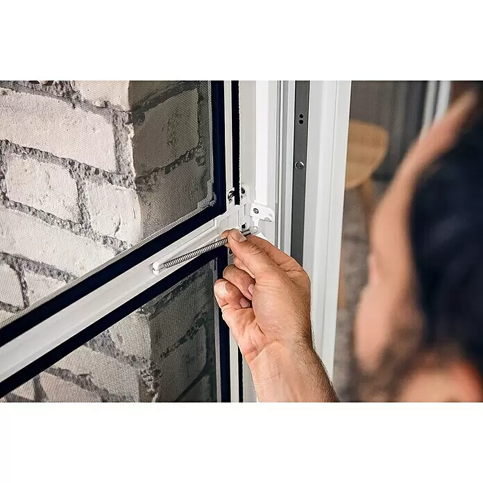 Tesa Insect Stop Puerta con protección contra insectos Falt - Blanco, Montaje de la mosquitera: Pinzas - Pestillo blanco con resorte siendo instalado a mano en un marco de mosquitera, fijándolo.