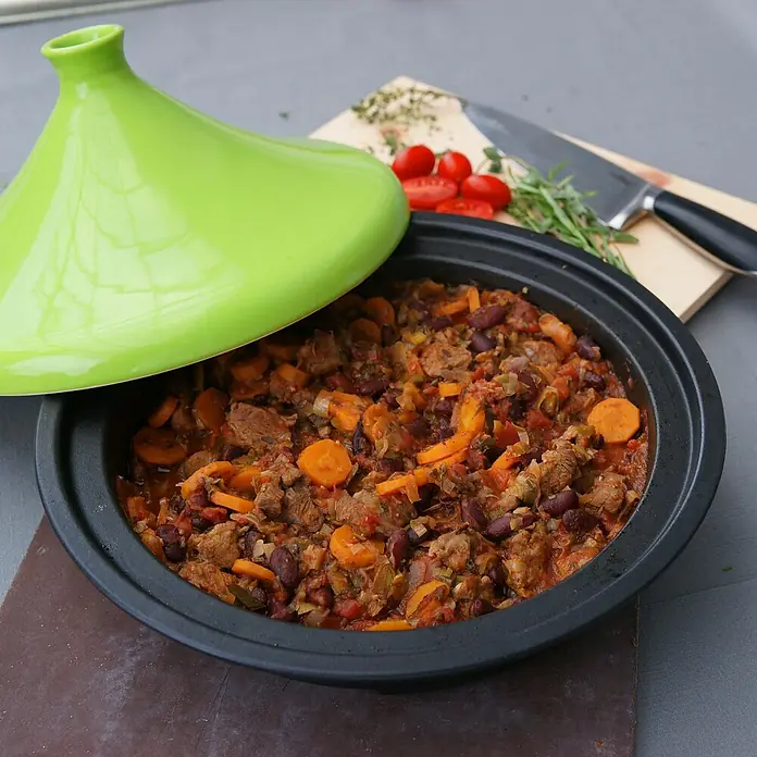 Outdoorchef Grillpfanne Barbecue Tajine - L x B: 43,6 x 39,6 cm, Höhe: 7,5 cm, Gusseisen - Tajine mit Fleisch und Gemüse, serviert in einem traditionellen marokkanischen Kochtopf mit grünem Deckel. Köstliche Mahlzeit!