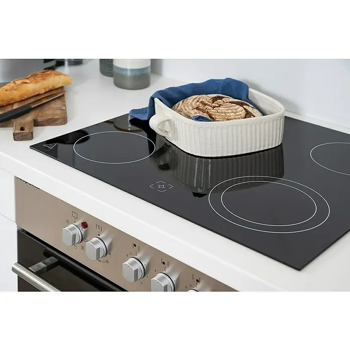 Respekta Premium Küchenzeile RP270WWCBO - Breite: 270 cm, Weiß, Mit Elektrogeräten - Nahaufnahme eines modernen Kochfelds mit Brot in einer Schüssel, das auf einer glänzenden Oberfläche steht. Die Bedienelemente des Ofens sind im Vordergrund zu sehen.