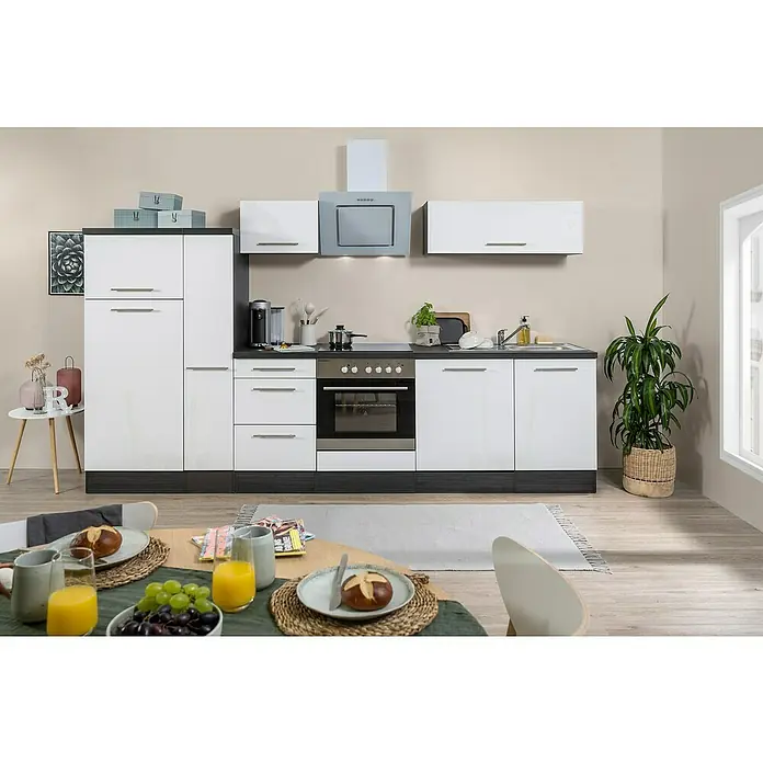 Respekta Premium Küchenzeile RP310EWCBO - Breite: 310 cm, Weiß, Mit Elektrogeräten - Küchenzeile mit weißen Schränken, dunkler Arbeitsplatte und modernen Geräten. Essbereich im Vordergrund mit frischen Speisen und Getränken.