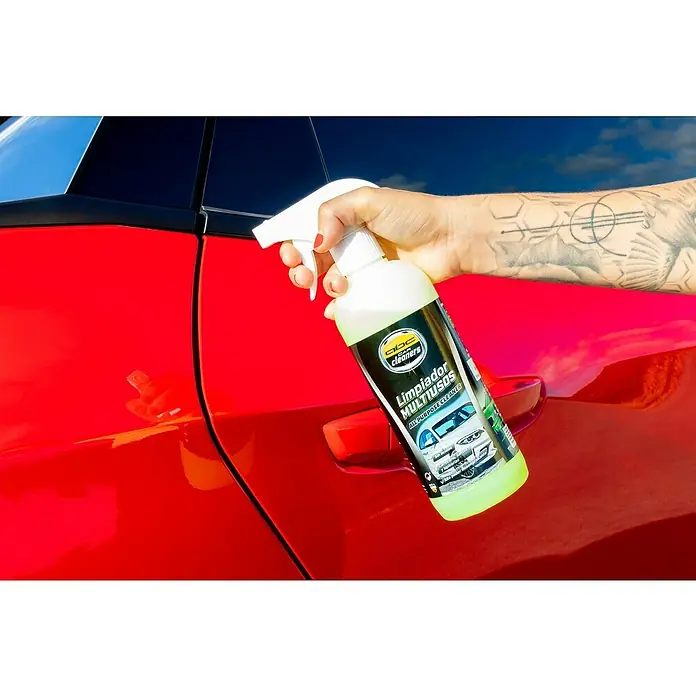 Limpiador multiusos MOT50007 - 500 ml - Una mano sujeta un pulverizador de ABC Car Cleaners limpiador multiusos delante de un coche rojo.
