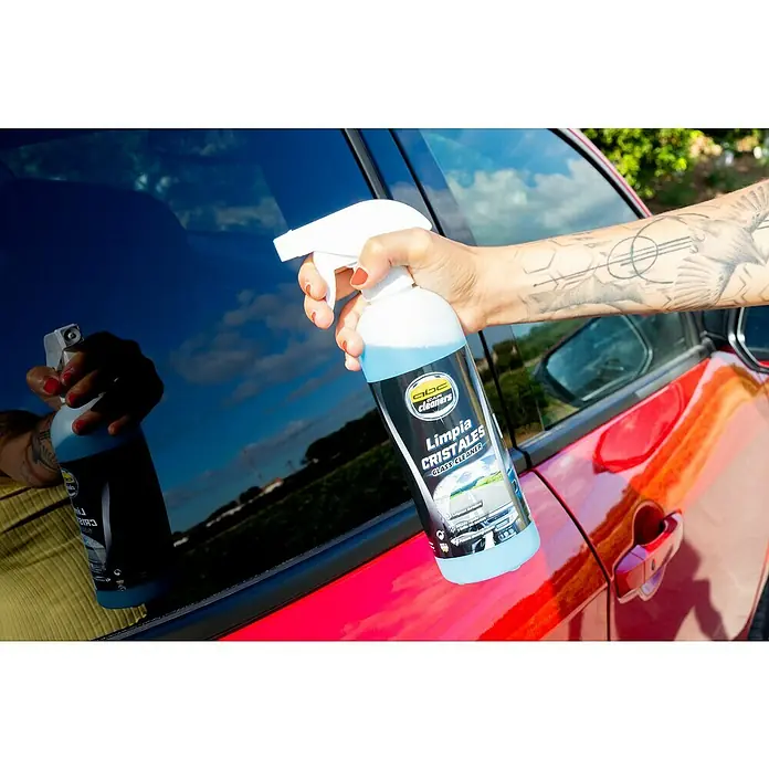 Limpiacristales MOT50005 - 500 ml - Primer plano de una persona rociando limpiacristales ABC Car Cleaners en la ventana de un coche rojo, con un tatuaje en el brazo.