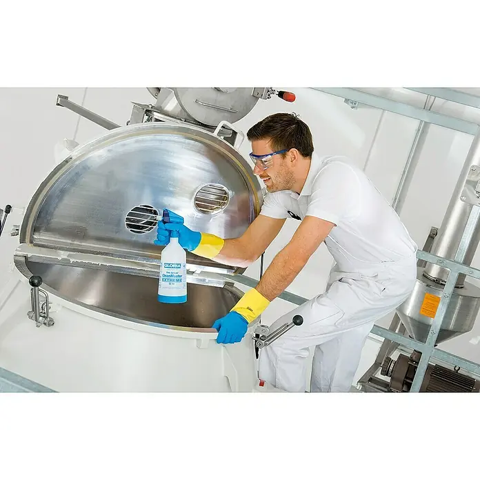 Gloria Feinsprüher Clean Master EXTREME EX 10 - Füllmenge: 1 l, Geeignet für: Desinfektionsmittel - Ein Mann reinigt eine große Maschine mit Gloria CleanMaster EX 10 Sprühflasche, Schutzbrille und Handschuhen für sichere Anwendung.