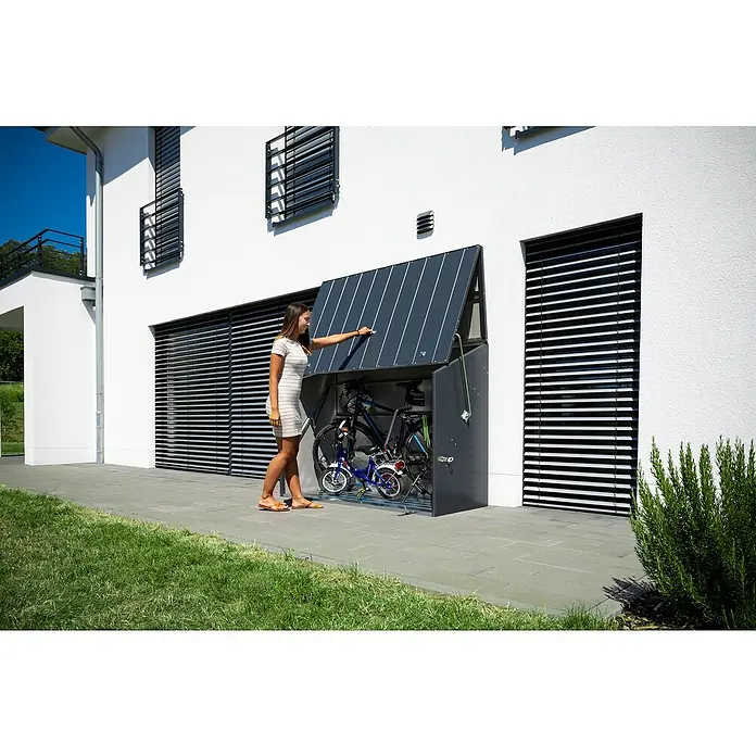 Trimetals Fahrradgarage - 185 x 76 x 139 cm, Stahl - Frau öffnet eine moderne Fahrradgarage aus Metall mit Platz für mehrere Fahrräder, die vor einem weißen Gebäude steht.