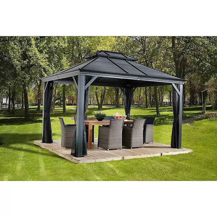 Sojag Standard-Pavillon Mykonos 10x12 - B x T: 364 x 299 cm, Anthrazit, Aluminium - Dunkelgraues Metallpavillon mit Wellblechdach und schwarzen Vorhängen, schützt Holztisch und Korbstühle auf einer Holzterrasse im Garten.