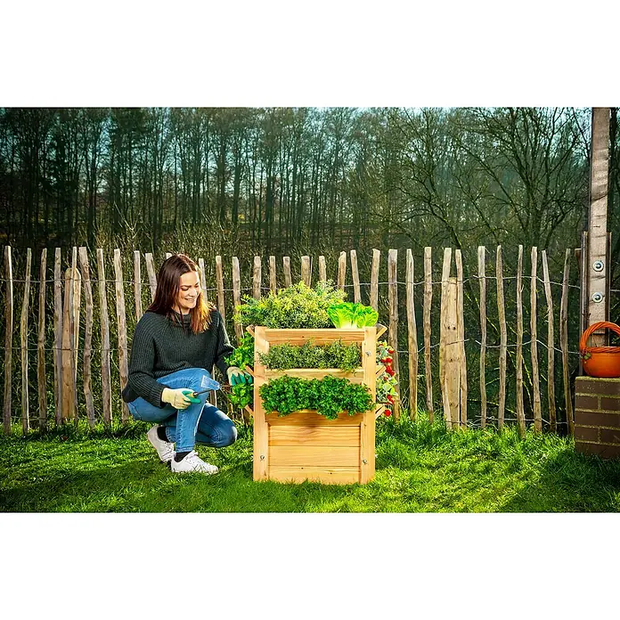 Westmann Hochbeet Premium L - 65 x 65 x 73 cm, Holz, Natur - Frau arbeitet an einem hölzernen, vertikalen Pflanzgefäß mit frischen Kräutern und Gemüse in einem Garten.