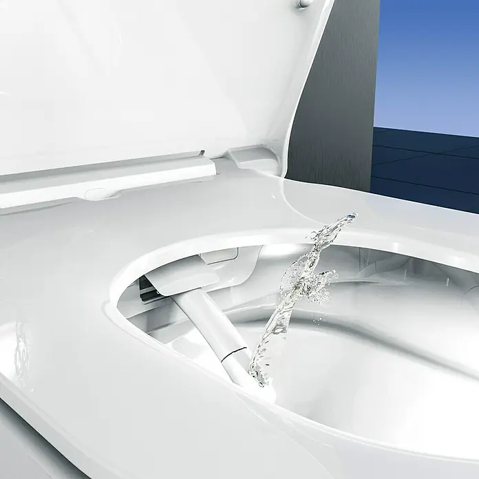 Camargue Wand-Dusch-WC-Set Moderno E-Clean - Spülrandlos, Mit schmutzabweisender Glasur, Spülform: Tief, WC Abgang: Waagerecht, Weiß - Nahaufnahme einer Toilette mit Bidetfunktion in Weiß mit aus dem Bidet austretendem Wasserstrahl, moderne Badezimmerausstattung.