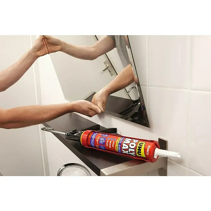 UHU Adhesivo para montaje High tack - Blanco, 450 g - Un adhesivo rojo UHU Poly Max reposa en una estantería con herramientas, sugiriendo un proyecto de montaje de espejo.