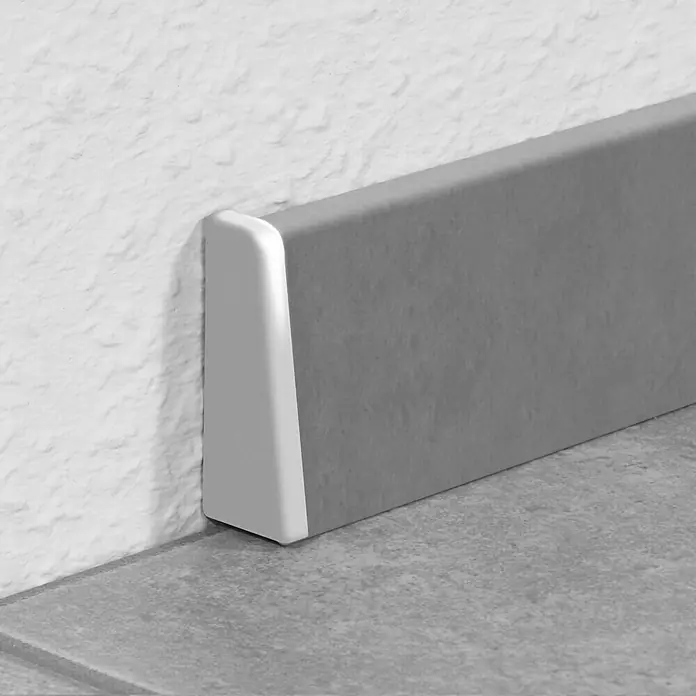 LOGOCLIC Endkappe K40 C - Silber, 2 Stk., Passend für: LOGOCLIC Sockelleiste K40 C - Nahaufnahme einer grauen Sockelleiste mit weißer Endkappe, die an einer strukturierten Wand und einem Fliesenboden befestigt ist.