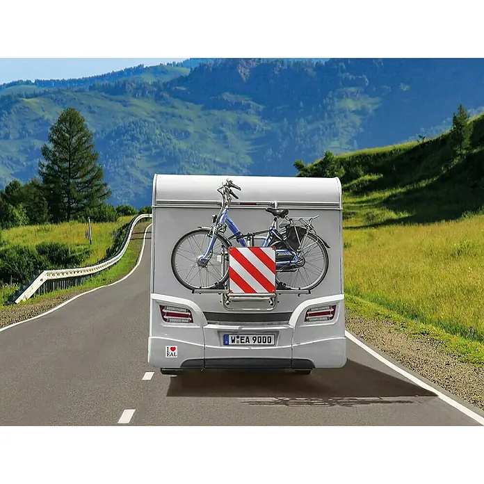 Calima Warntafel - L x B: 50 x 50 cm, Doppelseitig, Geeignet für: Einsatz in Spanien & Italien - Heckansicht eines Wohnwagens mit Fahrradträger und einem blauen Fahrrad darauf, auf einer malerischen Straße.
