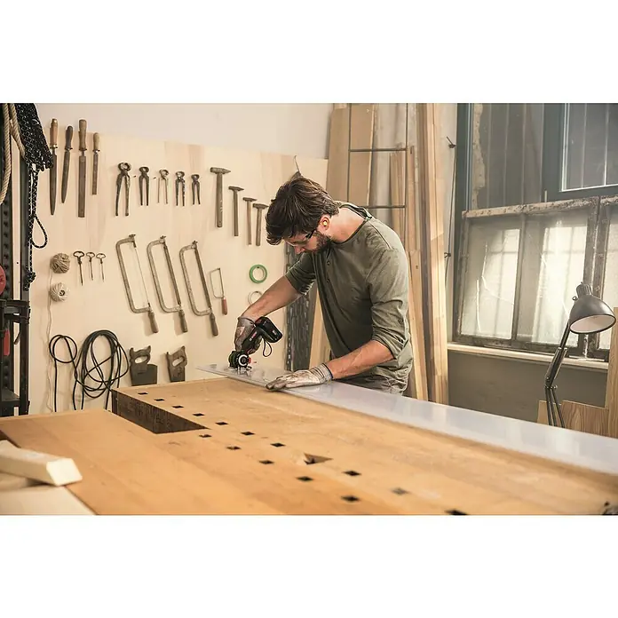 Bosch Power for All 18V NanoBlade-Säge AdvancedCut 18 - Leerlaufdrehzahl: 7.000 U/min, 18 V, 1 Akku - Ein Mann in Werkstatt mit einer oszillierenden Multifunktionswerkzeug zum Schneiden von Materialien auf einer Werkbank.