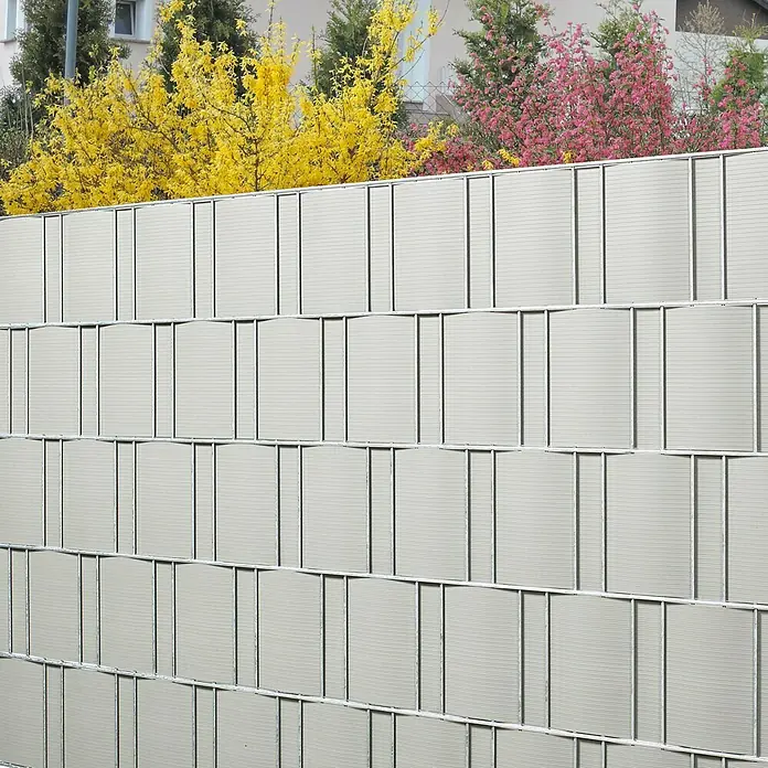 Stabilit Sichtschutzstreifen - Silbergrau, 201,5 x 19,2 cm, 5 Stk. - Nahaufnahme eines modernen grauen Sichtschutzzauns mit horizontalen Lamellen und blühenden Büschen im Hintergrund.