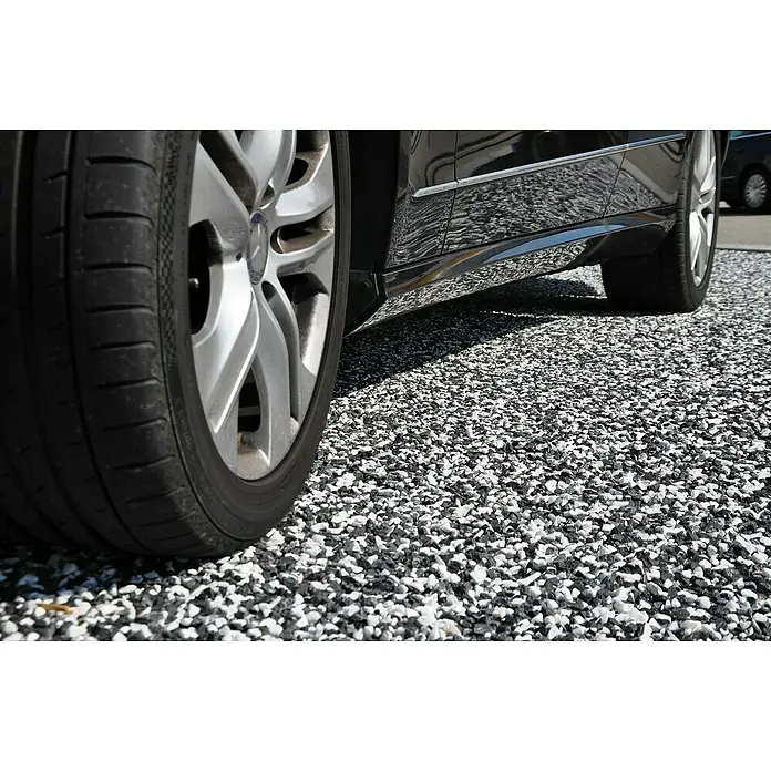 Stabilisierungsmatte Kiesfix - 120 x 80 cm, Polyethylen - Nahaufnahme eines schwarzen Autos mit silbernen Felgen auf einem Kiesweg. Das Bild betont die Details des Autos und des Untergrunds.