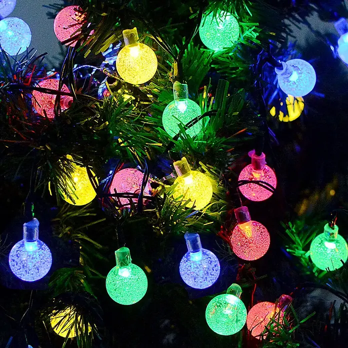 Arte confort Guirnalda luminosa solar Stella - Largo: 650 cm, LED - Un primer plano de bolas de Navidad coloridas e iluminadas que cuelgan de un árbol de Navidad, creando un ambiente festivo.