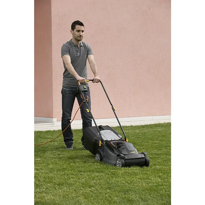 Alpina Cortacésped eléctrico BL320E - 1.000 W, Ancho de corte: 32 cm - Un hombre está cortando el césped con un cortacésped eléctrico Alpina con un cesto de recogida de hierba. El cortacésped es negro con detalles amarillos.