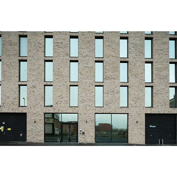 Celina Klinker Verblendstein Handstrich Valencia - 21,5 x 6,5 cm, Beige, Steinoptik - Fassade eines modernen Gebäudes mit rechteckigen Fenstern und einer markanten Backsteinfassade, die architektonische Details hervorhebt.
