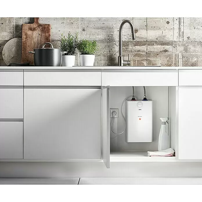 AEG Termo eléctrico U5 - 5 l, 2.000 W, Rango de temperaturas: 30 °C - 85 °C, Montaje bajo mesa - Calentador de agua eléctrico blanco instalado bajo un fregadero de cocina moderno, visible en un armario abierto.