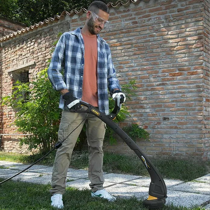 Alpina Elektro-Rasentrimmer ATR 350 E - 350 W, Schnittbreite Faden: 24 cm - Ein Mann im Garten, der mit einem ALPINA Rasentrimmer arbeitet, um sein Gras zu trimmen.
