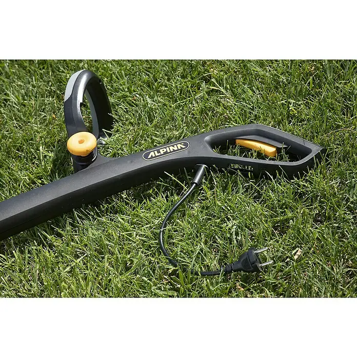 Alpina Elektro-Rasentrimmer ATR 350 E - 350 W, Schnittbreite Faden: 24 cm - Nahaufnahme eines schwarzen ALPINA Rasentrimmers mit gelben Akzenten, der auf grünem Gras liegt und einen Elektrostecker hat.