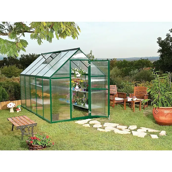 Palram – Canopia Invernadero Mythos - Medidas ext. (An x Pr): 185 x 306 cm, 4 mm, Verde - La imagen muestra un invernadero con puertas abiertas, rodeado de un jardín con sillas, bancos y plantas. El invernadero tiene marcos verdes.