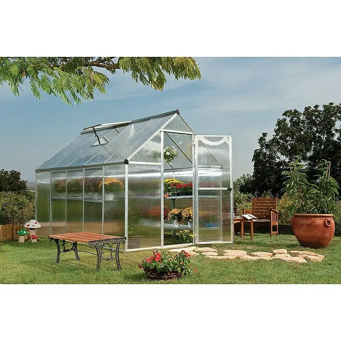 Palram – Canopia Gewächshaus Mythos - Außenmaß inkl. Dachüberstand (B x T): 185 x 306 cm, 4 mm, Silber - Gewächshaus im Garten mit geöffneter Tür, Bänken und Pflanzen. Ideal für Hobbygärtner, bietet es Schutz und optimale Wachstumsbedingungen.