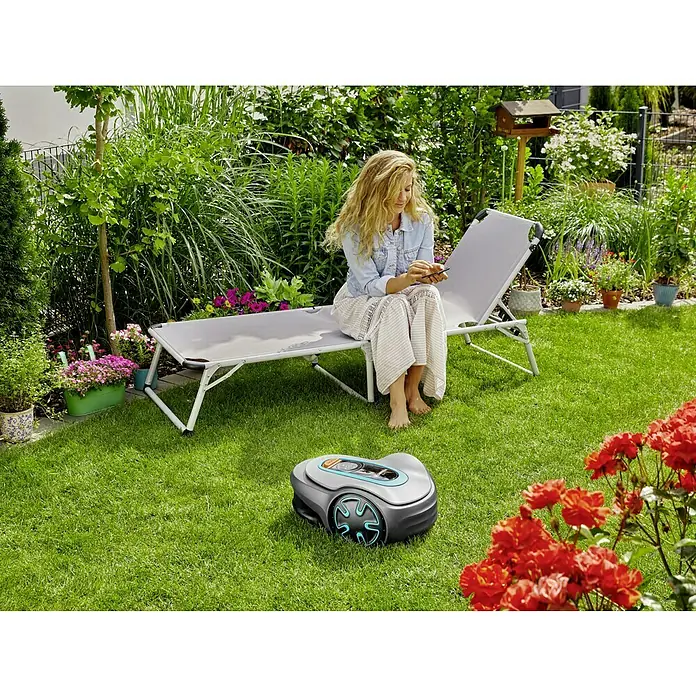 Gardena Mähroboter Sileno minimo 500 - 500 m², Schnittbreite: 16 cm, Induktionsgestützte Navigation, Begrenzungskabel - Frau entspannt auf Liege, während ein Gardena Mähroboter den Rasen mäht. Der Roboter sorgt für einen perfekten Schnitt.