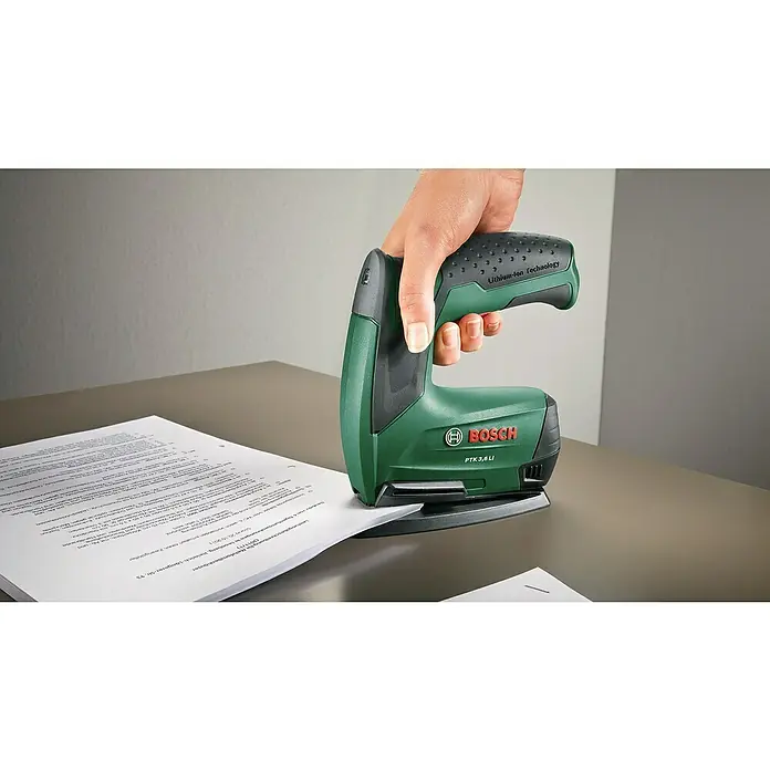 Bosch Akku-Tacker PTK 3,6 LI Office Set - 3,6 V, Klammertiefe: 4 mm - 10 mm - Nahaufnahme eines Bosch PTK 3,6 LI Akku-Tackers beim Heften von Papier. Das Gerät ist grün, schwarz und wird von einer Hand bedient.